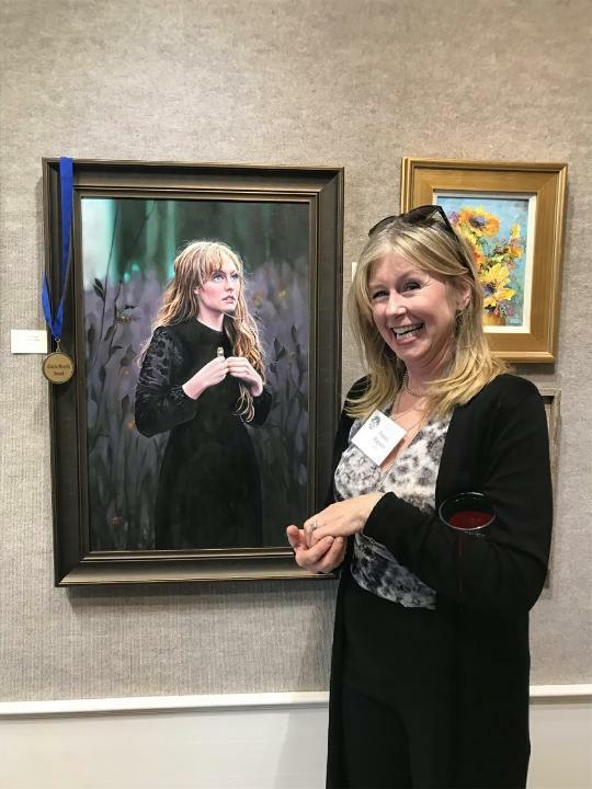 Photo of Tracey standing next to a painting that won an award